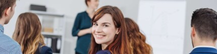 Lächelnde Frau dreht sich während eines Seminars zur Kamera
