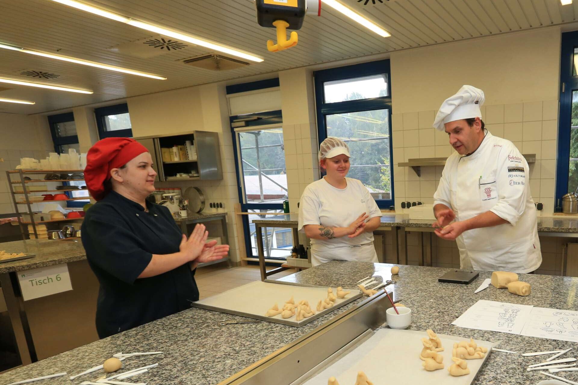 Branchenseite Bildungseinrichtungen, Auszubildende im Bäckerhandwerk mit ihrem Lehrmeister bei der Arbeit