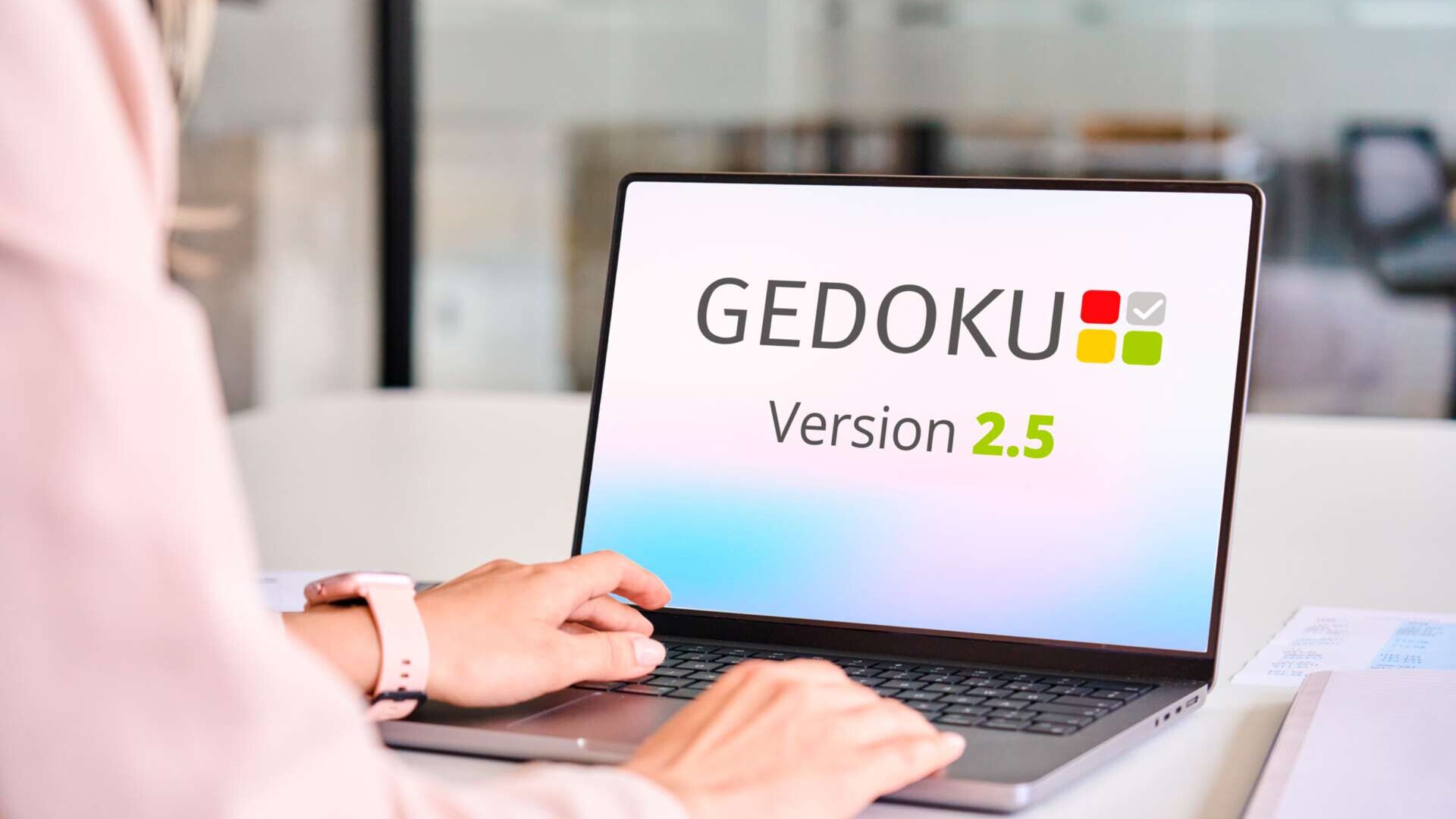 Eine Frau sitzt am Schreibtisch und öffnet auf dem Laptop die Software GEDOKU 2.5