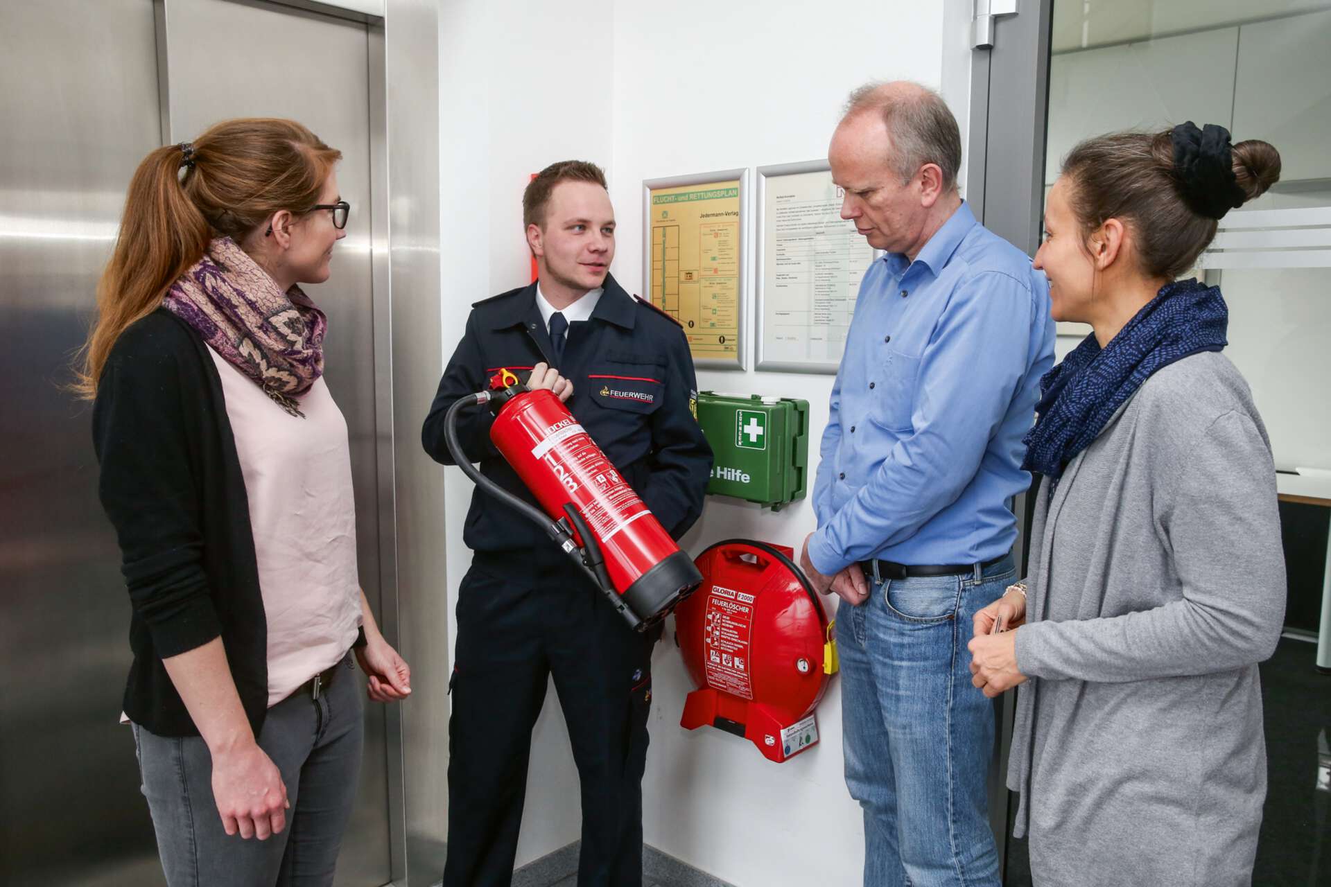 Eine Person zeigt einen Feuerlöscher drei weiteren Personen