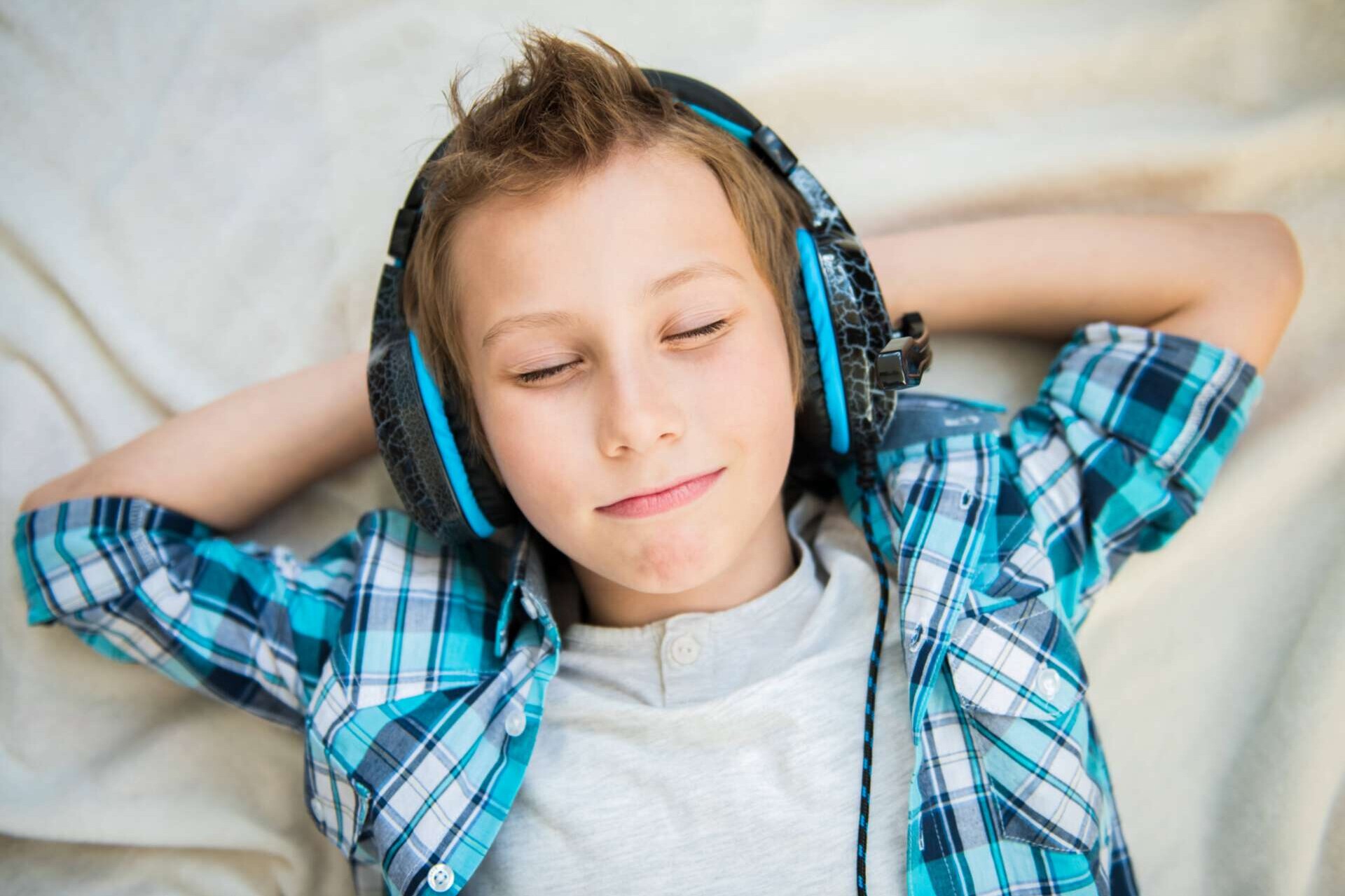 Junge mit aufgesetzten Kopfhörern  entspannt beim Musikhören