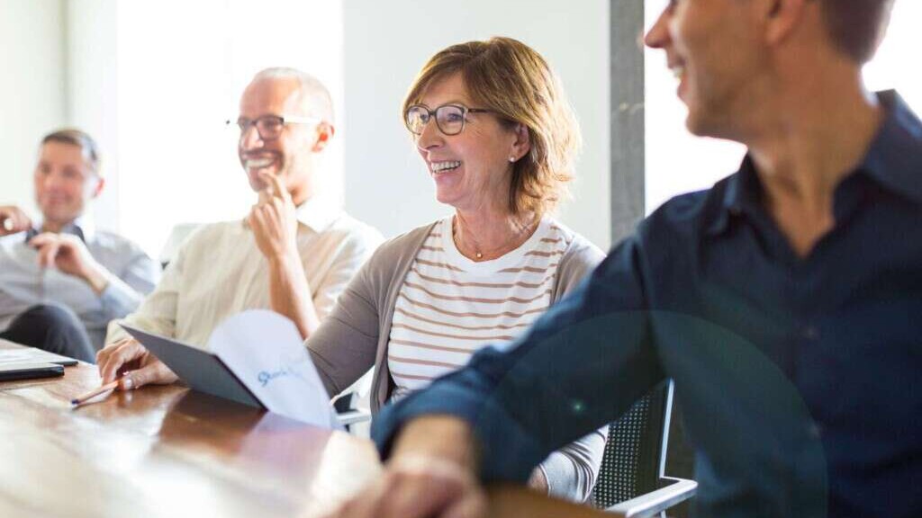Jahresbericht Headerbild. Menschen sitzen an einem Tisch.
