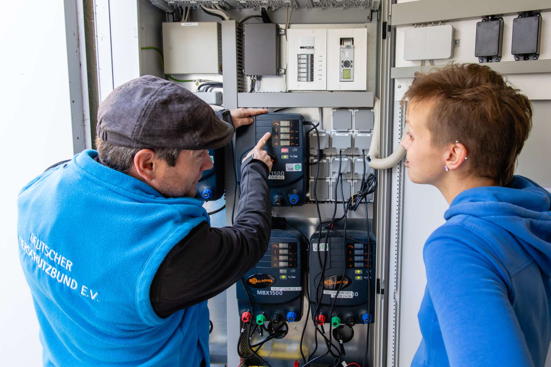Zwei Personen an einer elektrischen Schaltanlage im Tierheim. Es findet eine Unterweisung statt.