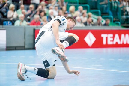 Handballspieler Nikola Bilyk hält sich nach einer Verletzung das rechte Sprunggelenk.