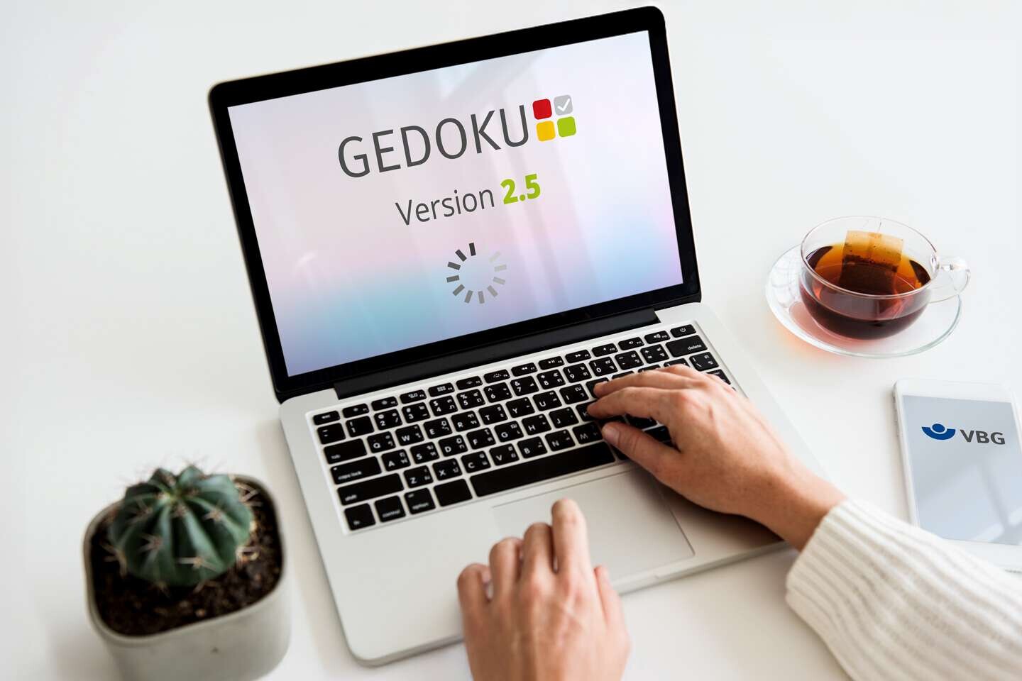 GEDOKU 2.5 - Mockup auf einem Laptop-Bildschirm ; am Laptop arbeitet eine Person, von der nur die Hände im Bild zu sehen sind.