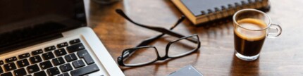 Arbeitsplatz mit Laptop, Mobiltelefon und Brille.
