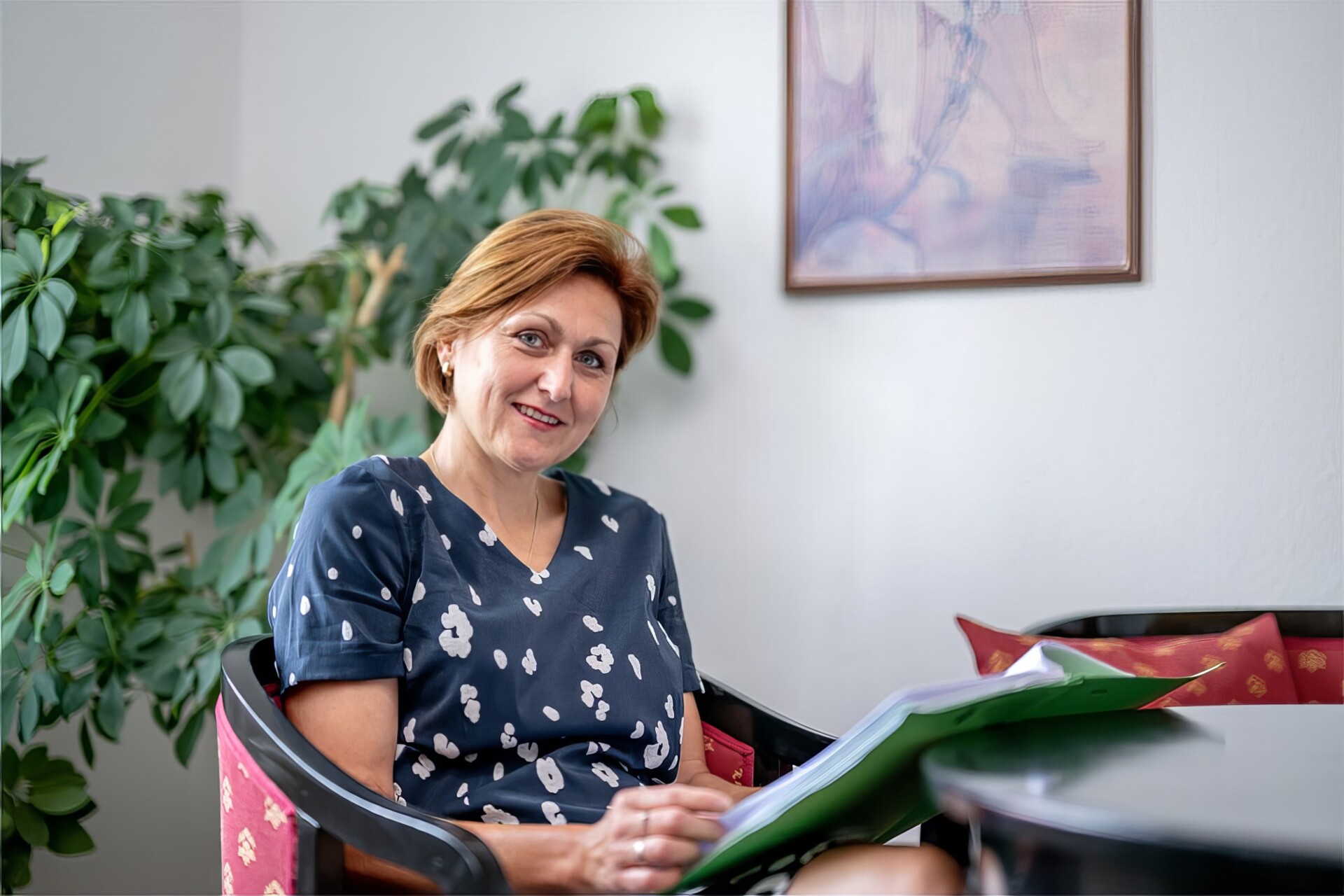 Foto von Petra Kirschnek die an einem Tisch mit einer Akte in der Hand sitzt.