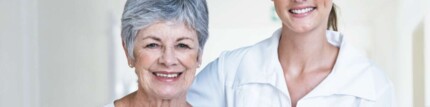 Pflegekraft stütz eine ältere Patientin in einem Krankenhausflur