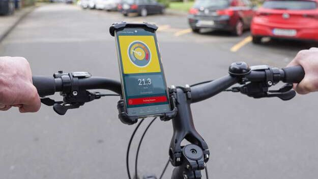 Fahradfahrer mit Handy in einer Halterung am Lenker. Die Drivometer-App wird auf dem Handy angezeigt.