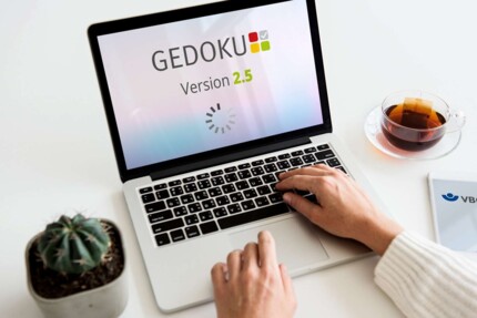 GEDOKU 2.5 - Mockup auf einem Laptop-Bildschirm ; am Laptop arbeitet eine Person, von der nur die Hände im Bild zu sehen sind.