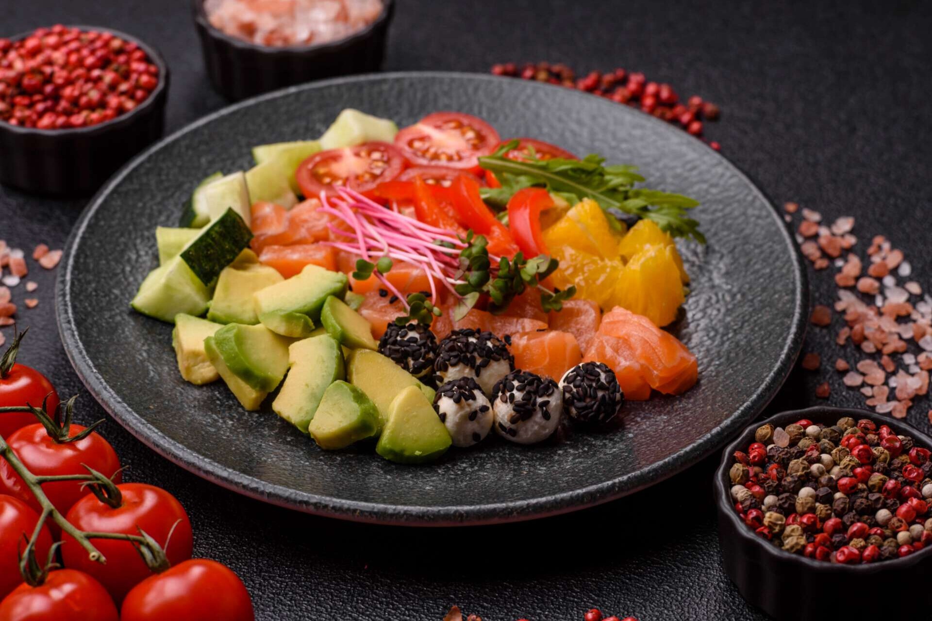 Schale mit Lachsstücken, Käse, Tomaten, Paprika und Avocado.