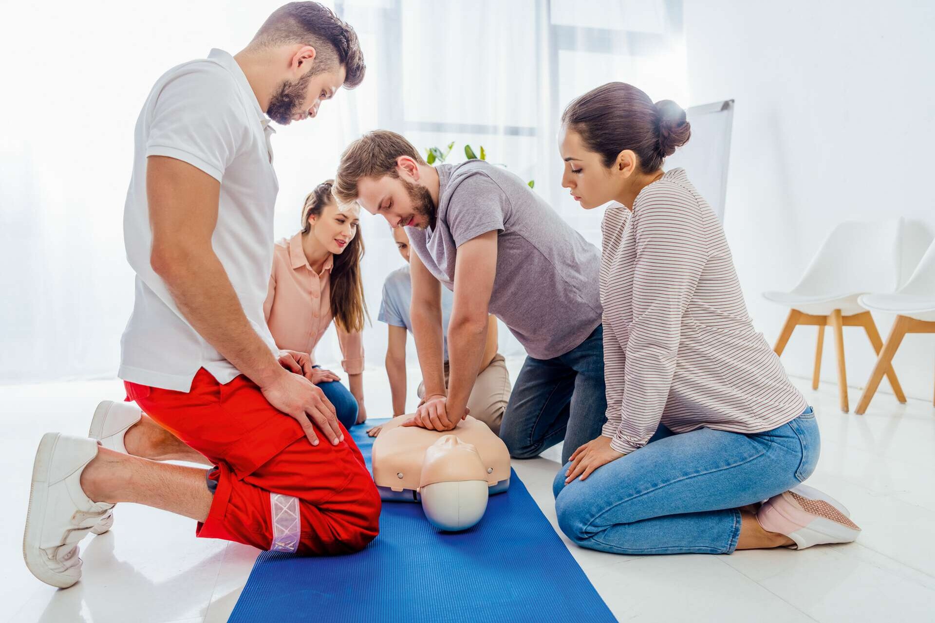 Herzdruckmassage an einer Puppe in einer Schulungssituation mit mehreren Personen