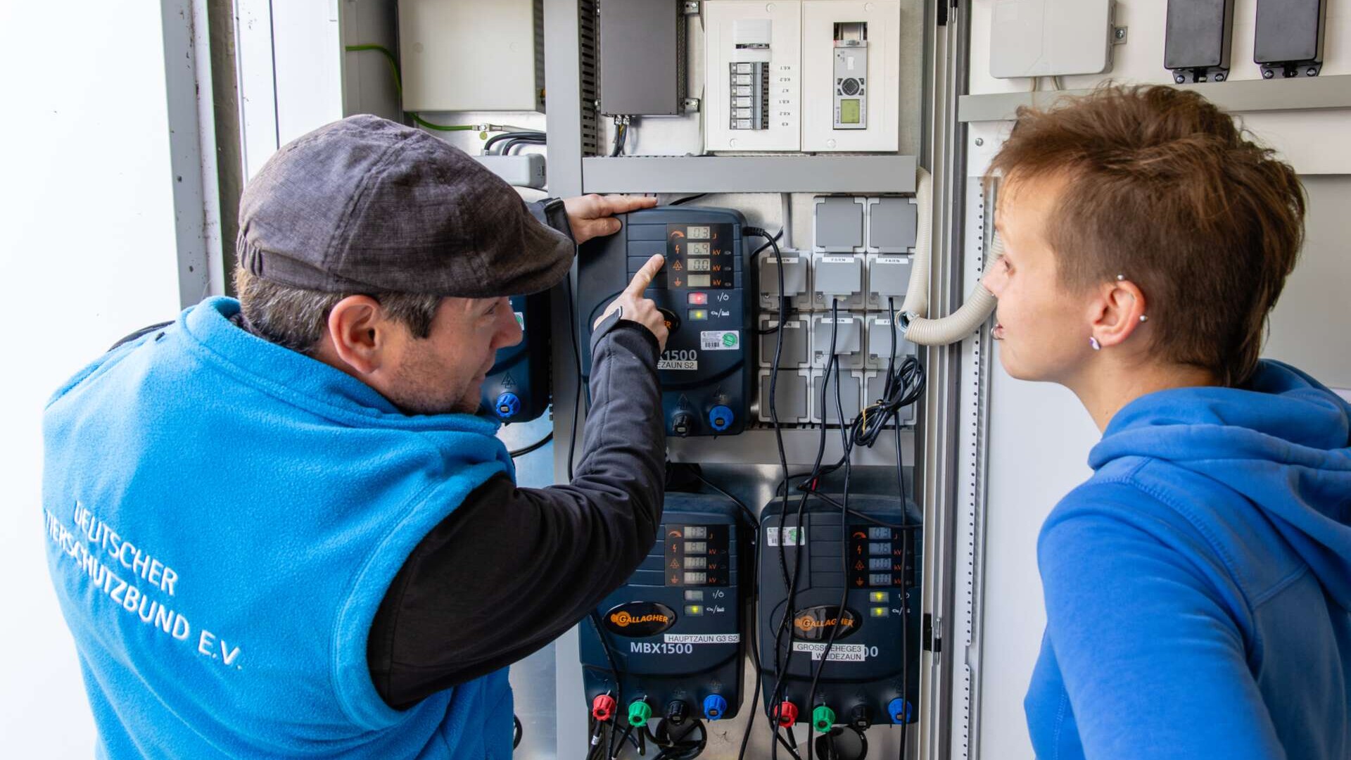 Zwei Personen an einer elektrischen Schaltanlage im Tierheim. Es findet eine Unterweisung statt.