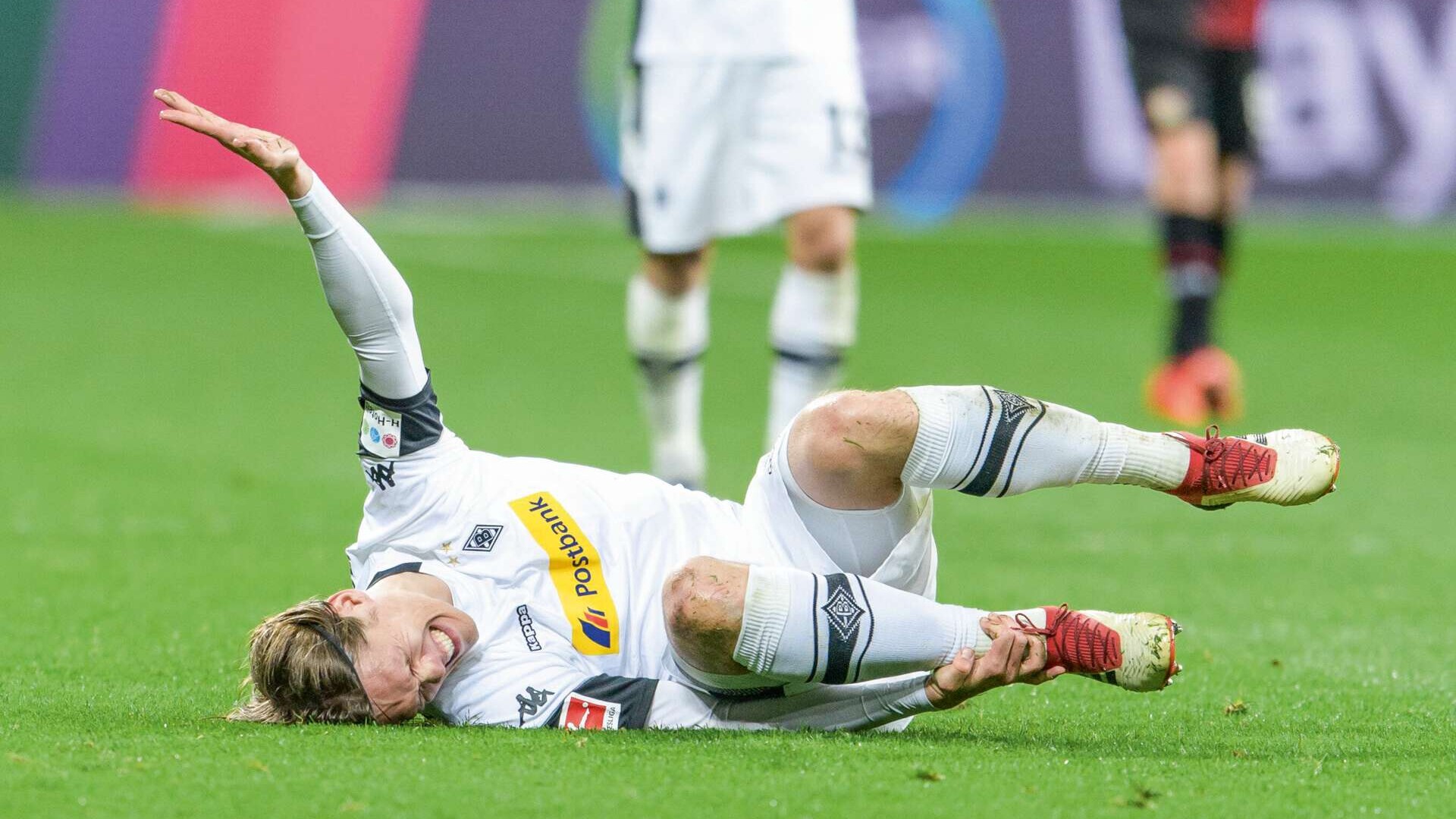 Verletzter Fußballspieler (Jannik Vestergaard) liegt mit schmerzverzerrtem Gesicht auf dem Spielfeld. 