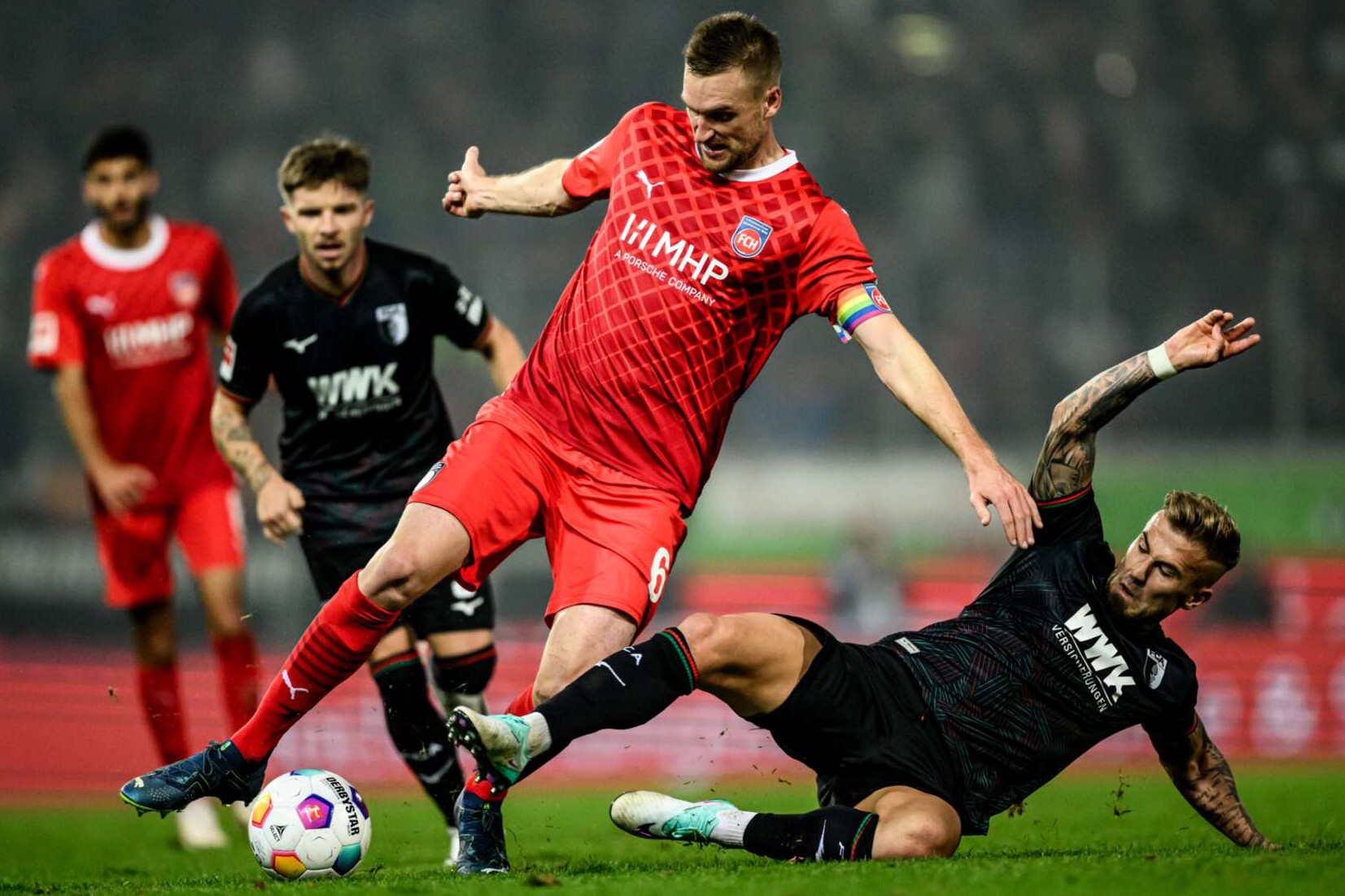 Der Augsburger Niklas Dorsch und Patrick Mainka vom 1. FC Heidenheim im Zweikampf während der Bundesliga-Partie am 22. Oktober 2023.