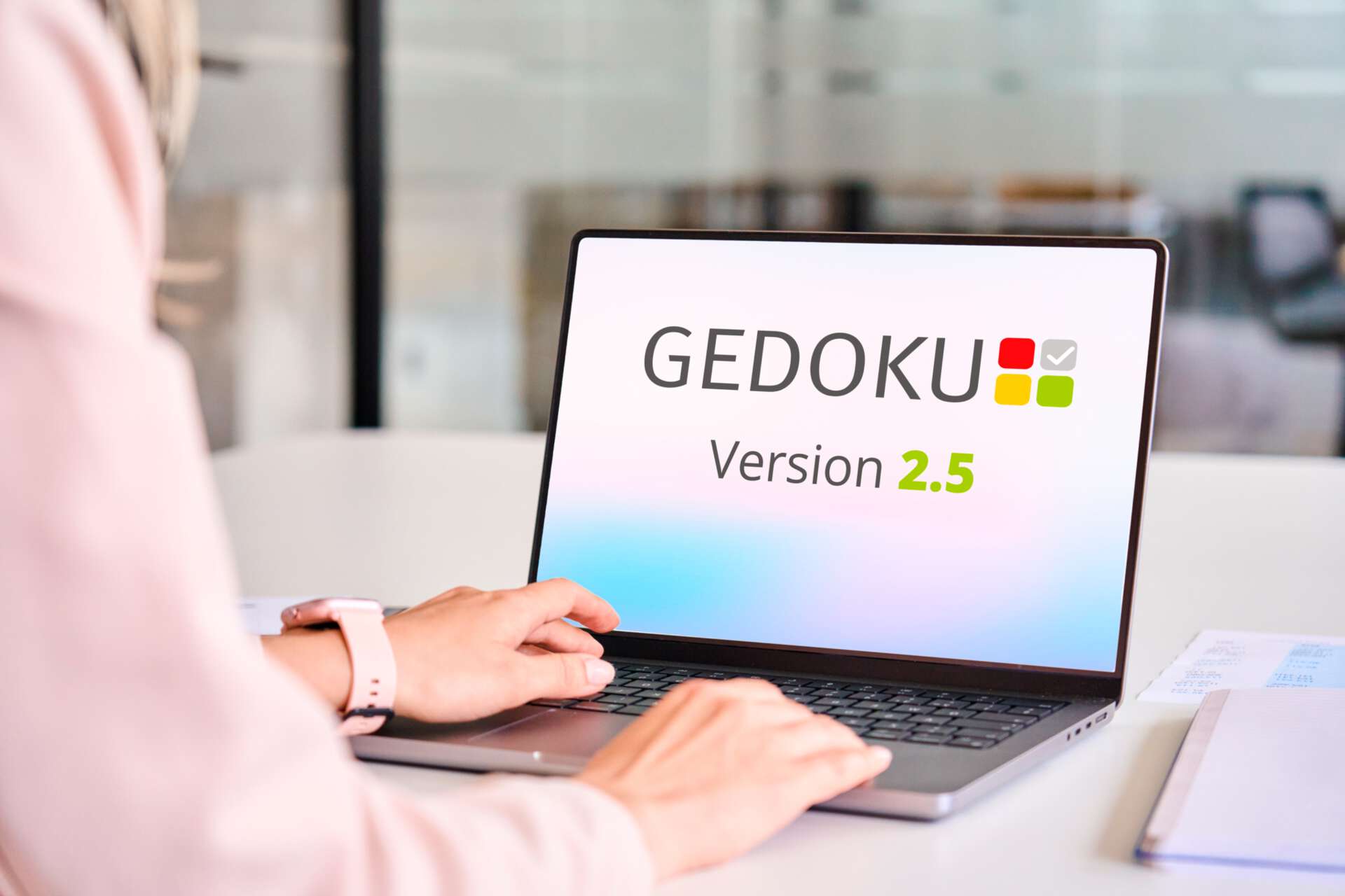 Eine Frau sitzt am Schreibtisch und öffnet auf dem Laptop die Software GEDOKU 2.5