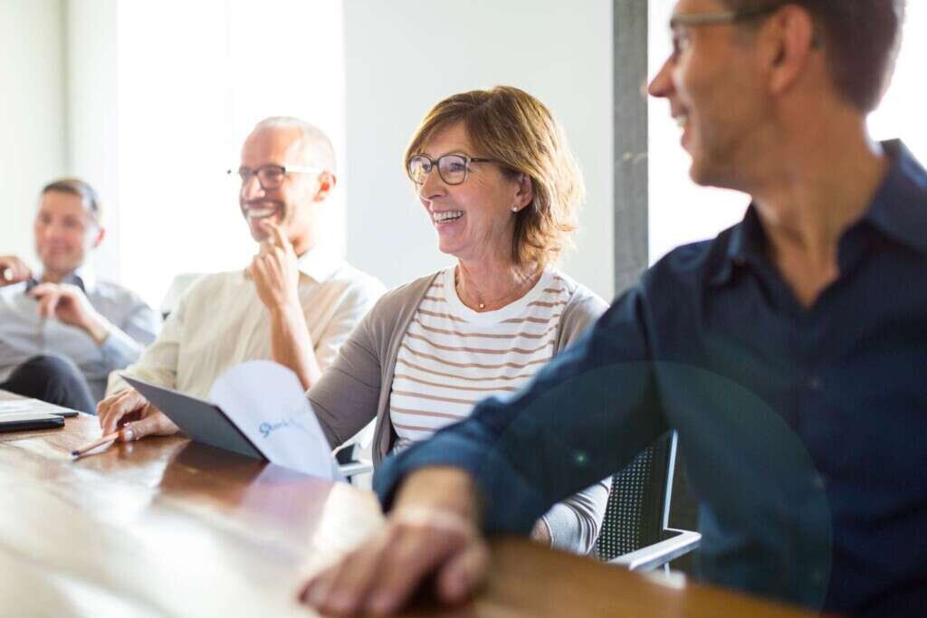 Jahresbericht Headerbild. Menschen sitzen an einem Tisch.