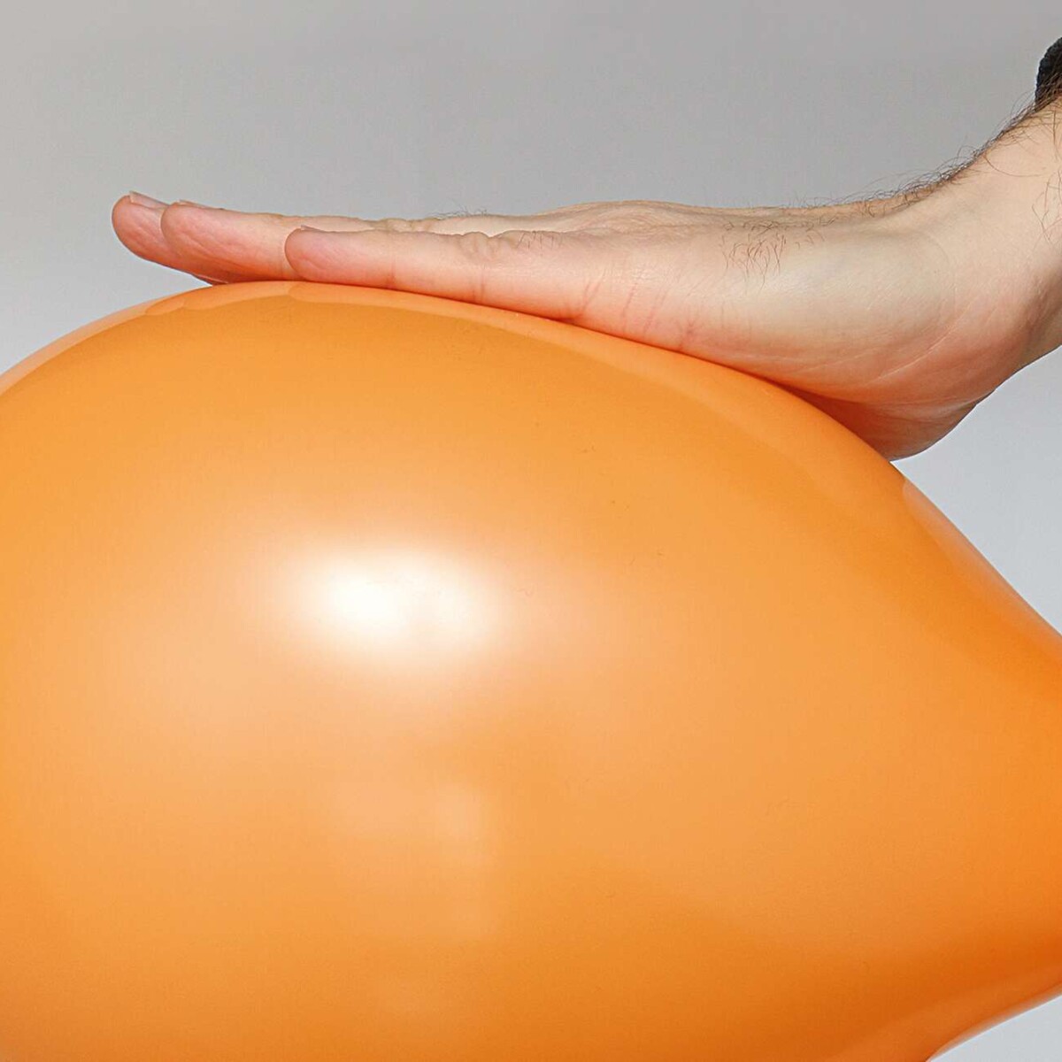 Relaunch vbg.de-Gefährdungsbeurteilung,  Symbolbild, mit der planen Handfläche leicht gedrückter aufgeblasener Luftballon