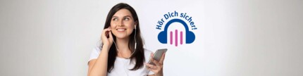 Frau mit Kopfhörern hält Handy in der Hand