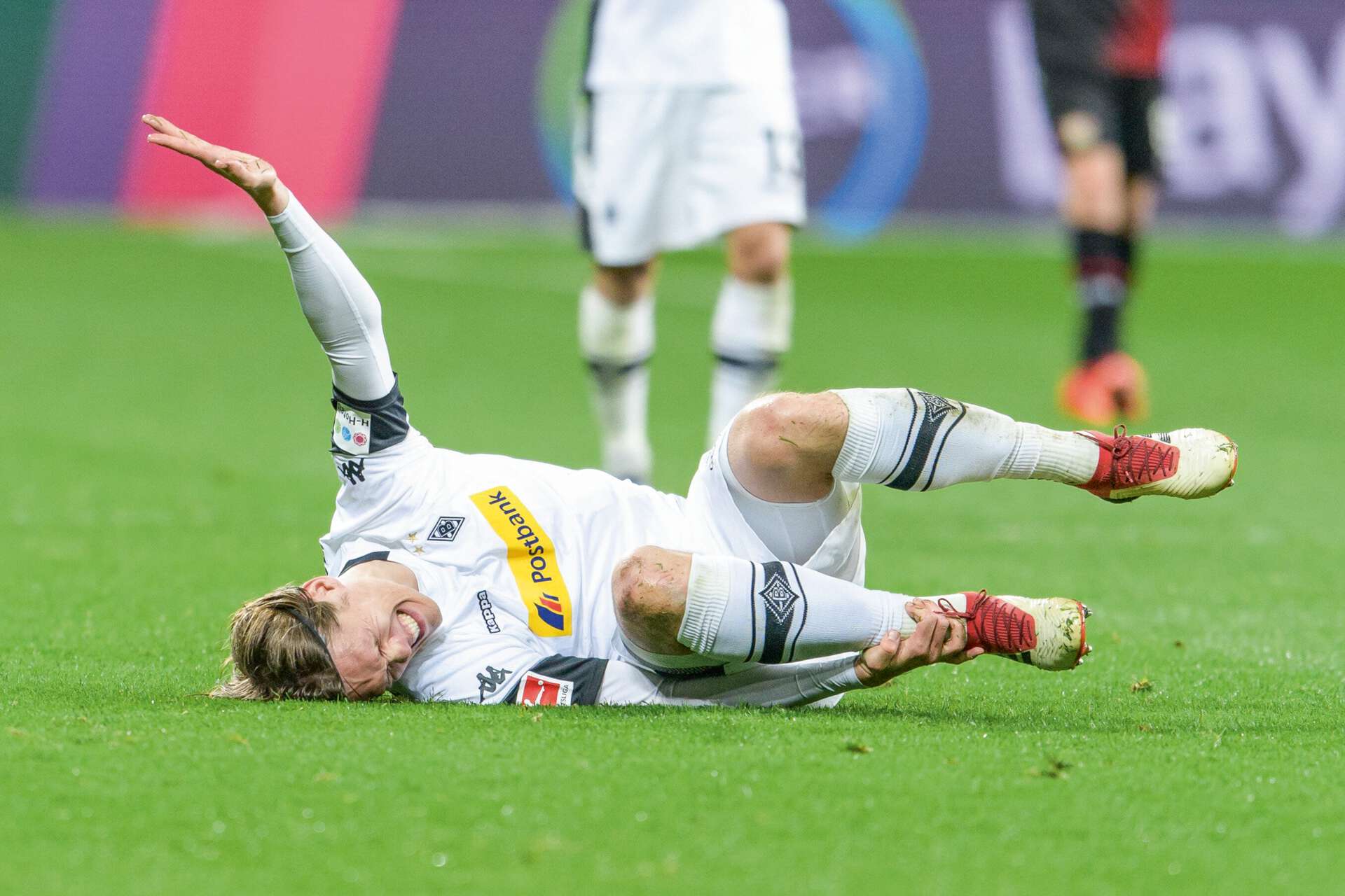 Verletzter Fußballspieler (Jannik Vestergaard) liegt mit schmerzverzerrtem Gesicht auf dem Spielfeld. 