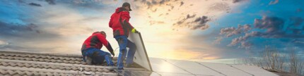 Zwei Personen montieren auf einem Dach eine Photovoltaikanlage