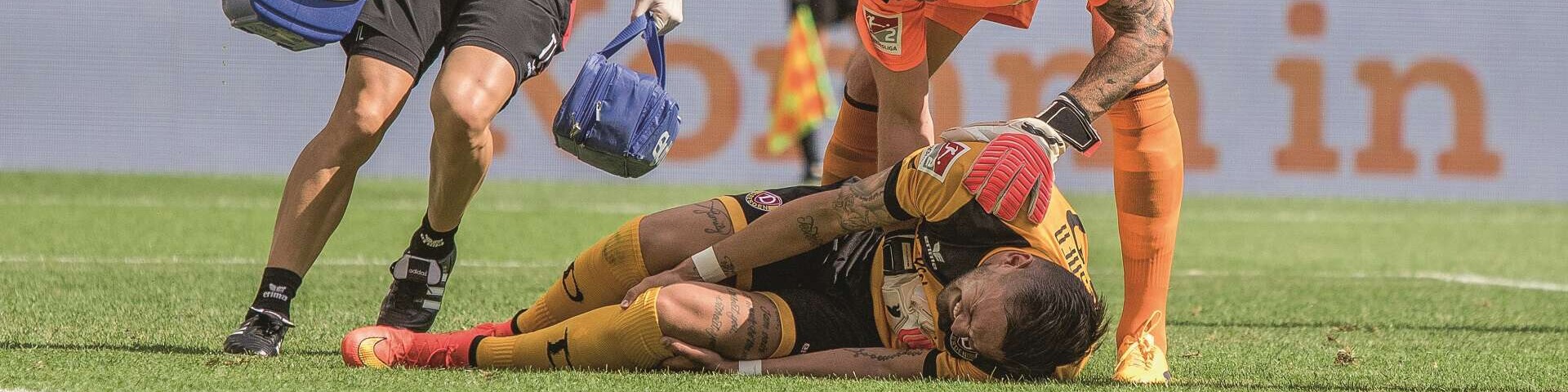 Pascal Testroet von Dynamo Dresden liegt verletzt auf dem Boden, Gegenspieler und medizinischer Betreuer kommen hinzu