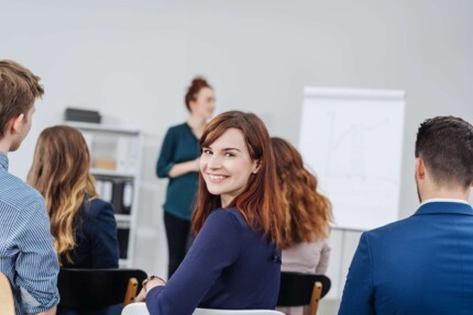 Lächelnde Frau dreht sich während eines Seminars zur Kamera