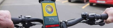 Fahradfahrer mit Handy in einer Halterung am Lenker. Die Drivometer-App wird auf dem Handy angezeigt.