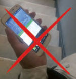 Person bedient Handy, während sie die Treppe nach unten geht.