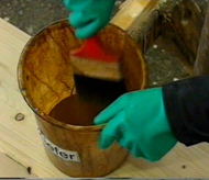 Mitarbeiter mit Schutzhandschuhen an Eimer mit Beize